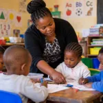 Teacher helping young children with learning activities in a community educare classroom in South Africa