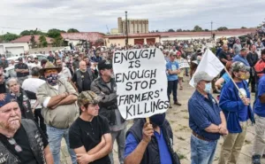 South African farmers and demonstrators gather at a protest against farm murders, holding placards demanding an end to killings.